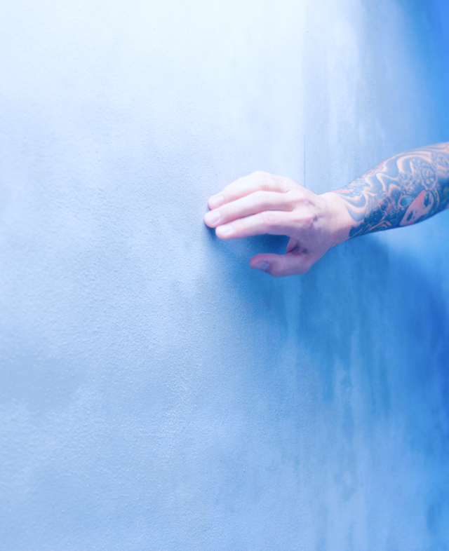 Hand fährt über bläuliche Wand